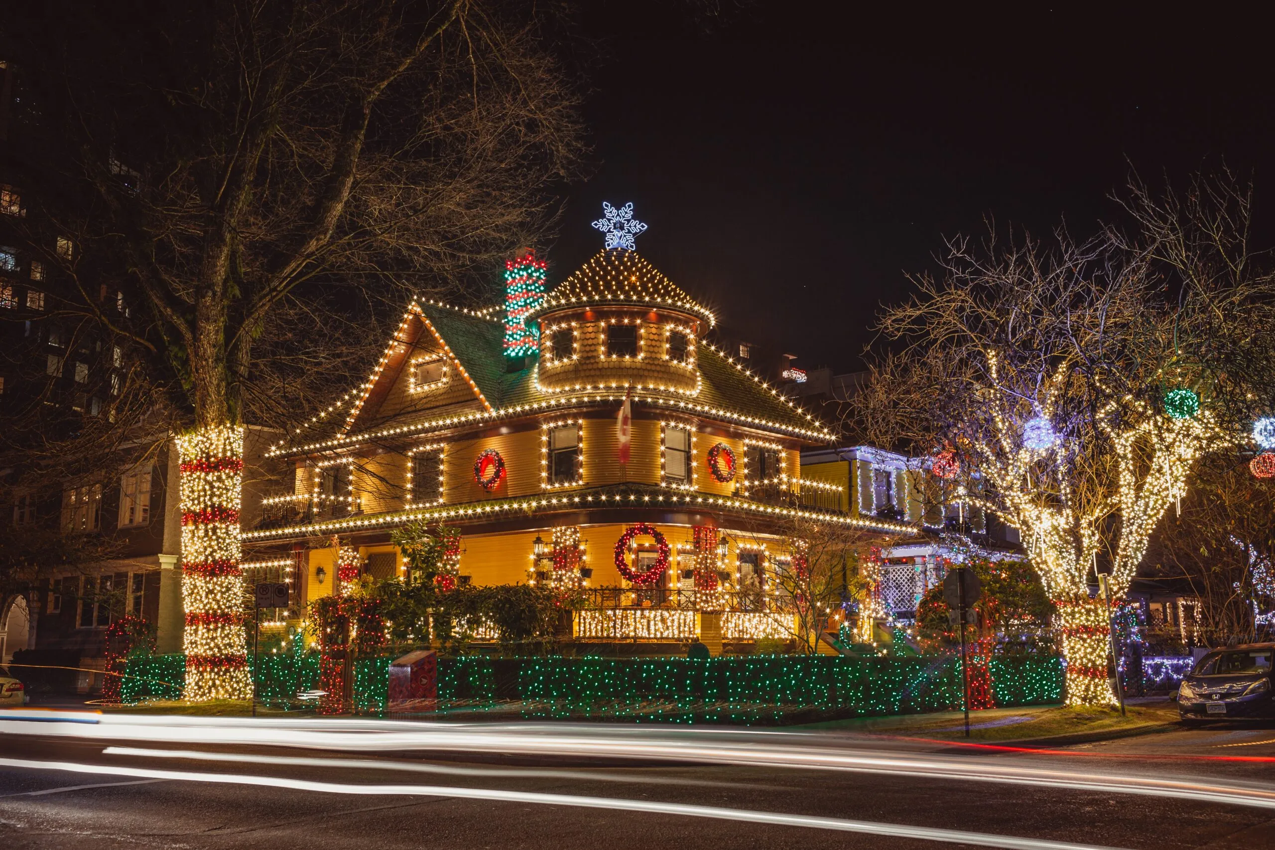 A large Ohio home outlined in warm Christmas lights on a snowy street at night